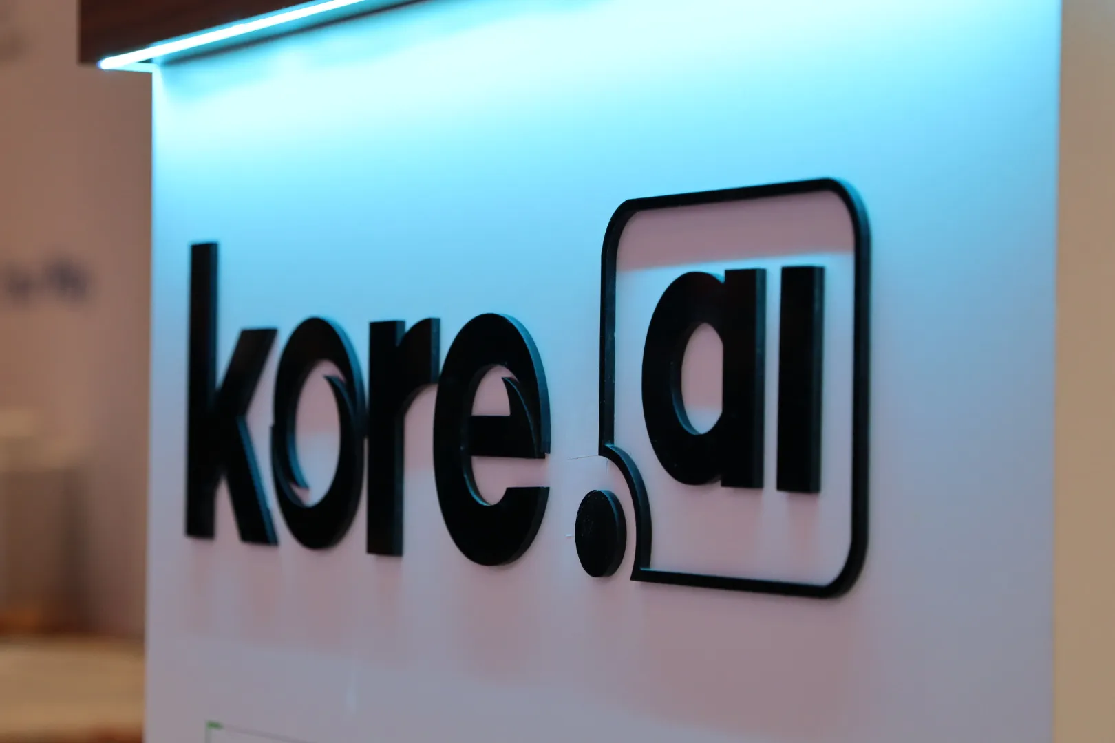 Dimensional backlit kore.ai logo mounted on a booth reception desk
