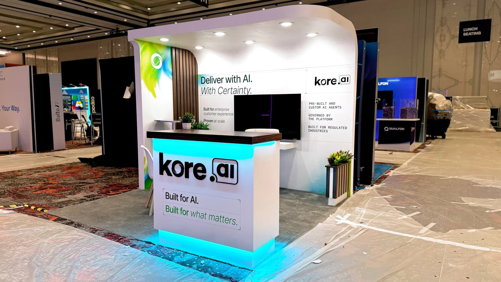 Light-toned kore.ai inline booth with a backlit reception desk, built by our team