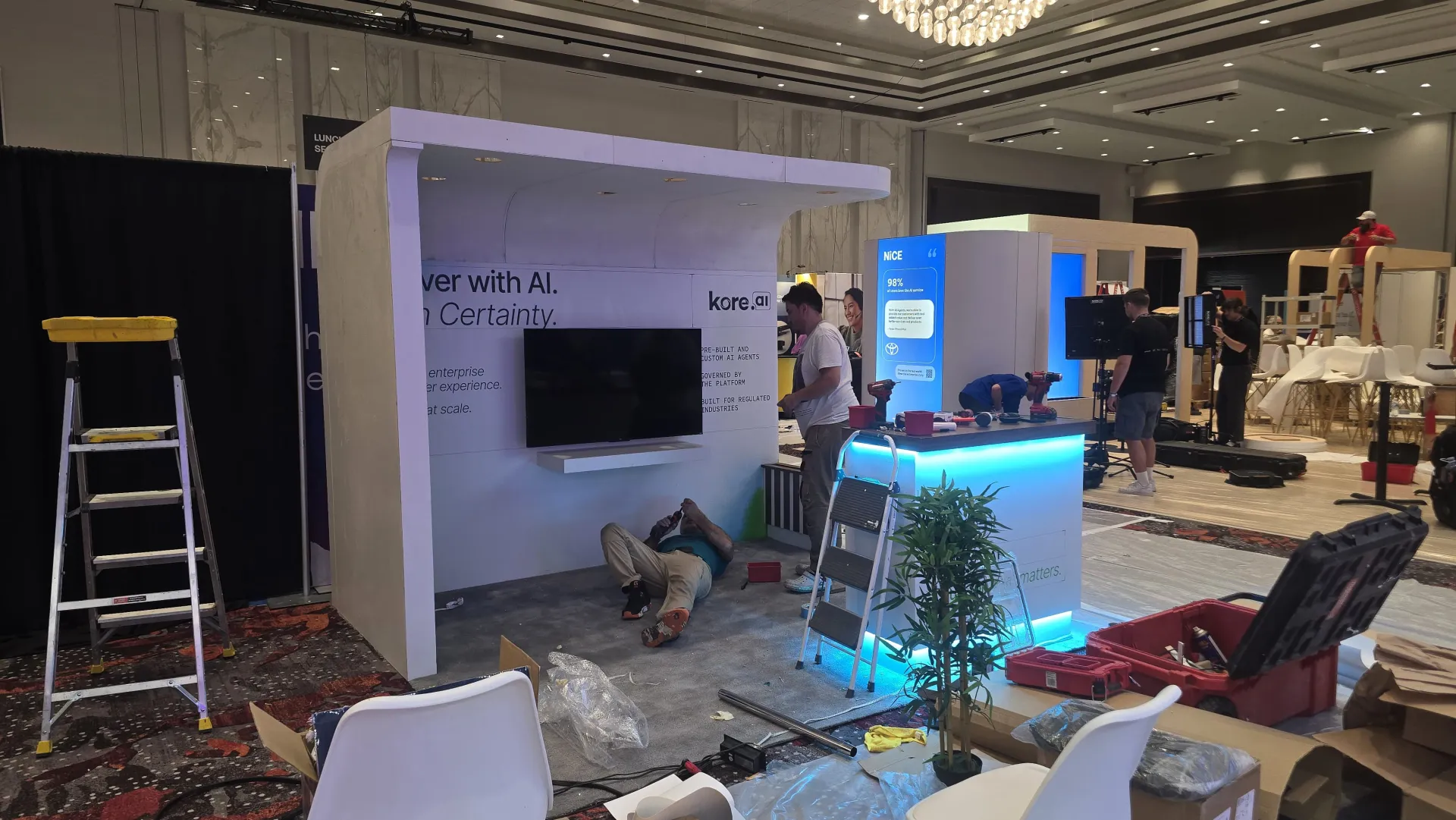 Vegas Vogue Expo crew installing a booth at Caesars Forum, with ladders, floor protection, and panels going up