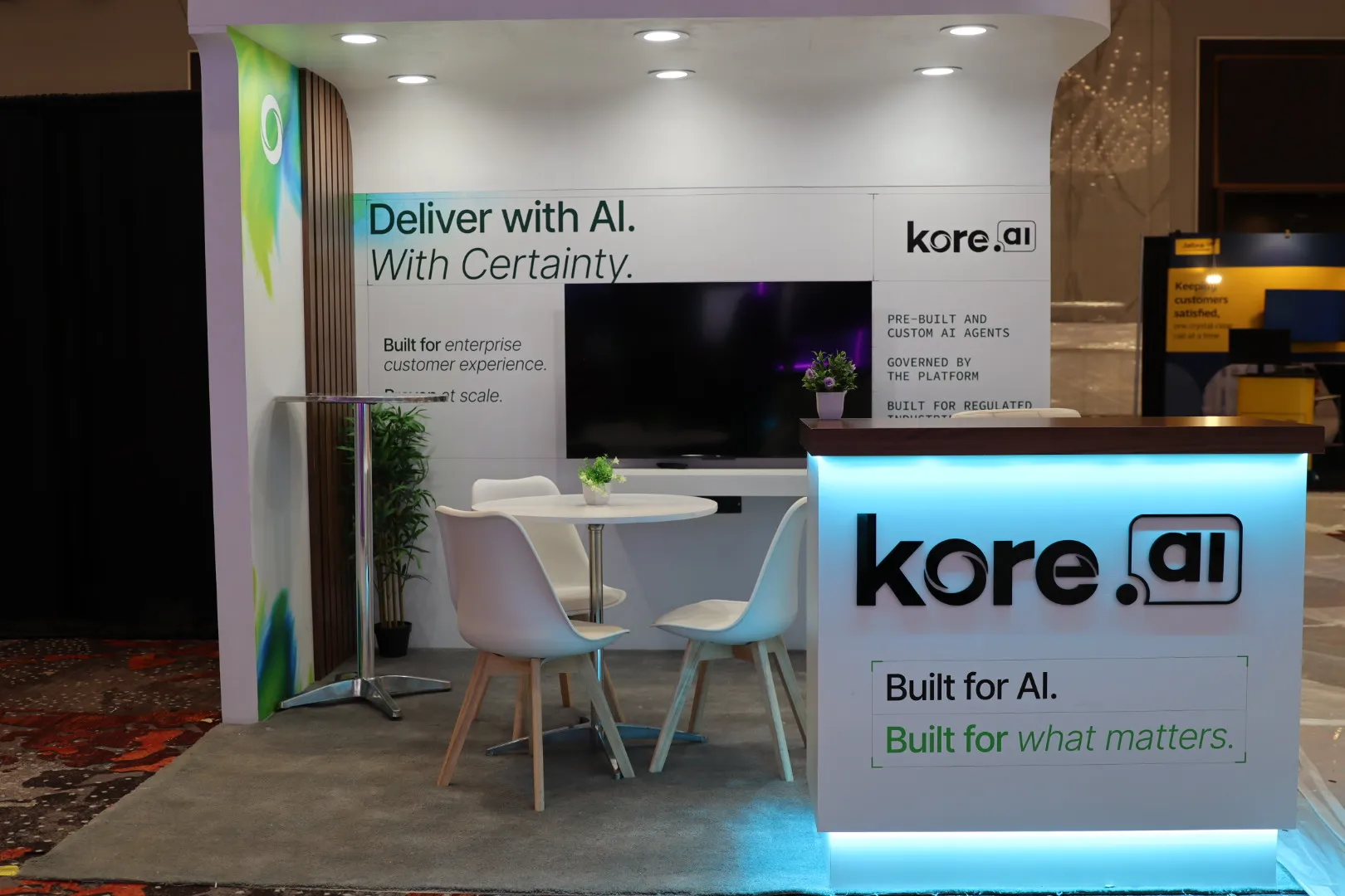 Backlit reception desk and private meeting nook inside a custom kore.ai exhibit